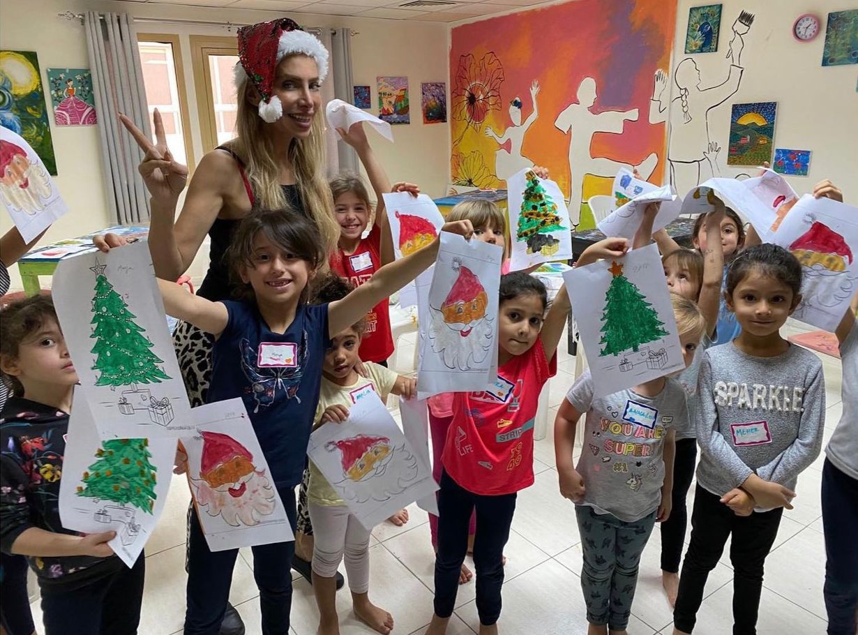 Children in art class holding up their paintings