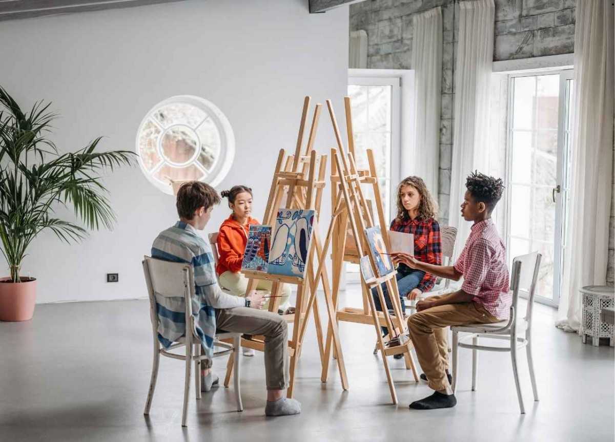 A group of children sitting in front of paintings and painting