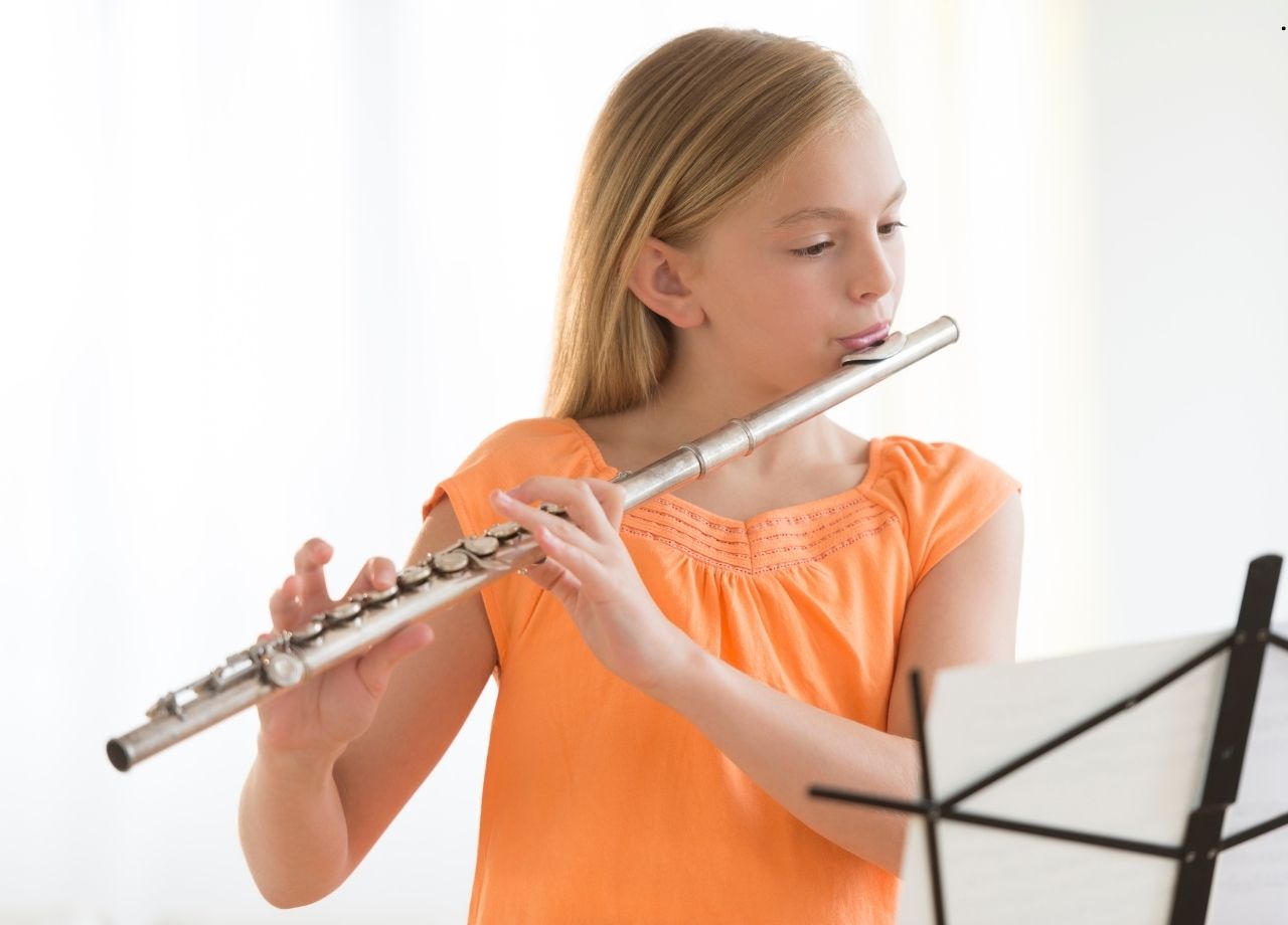 girl holding and playing a flute