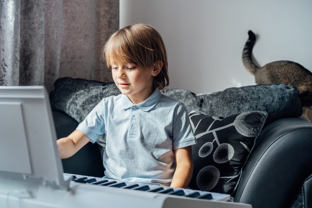 Small boy playing electric piano making music home leisure activity growing up education