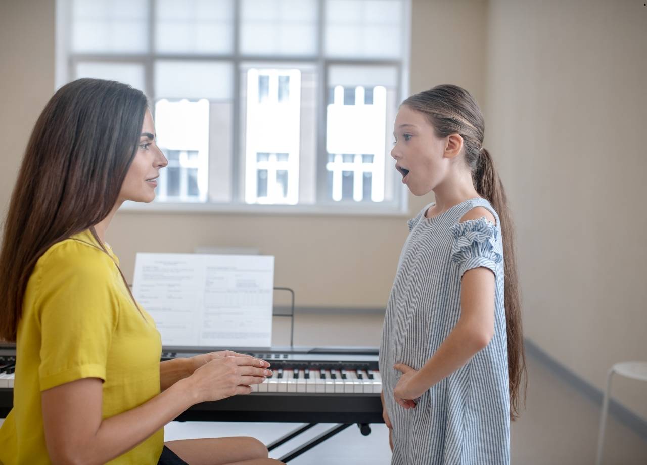 Mother sitting looking at her daughter as she coaches her to sing