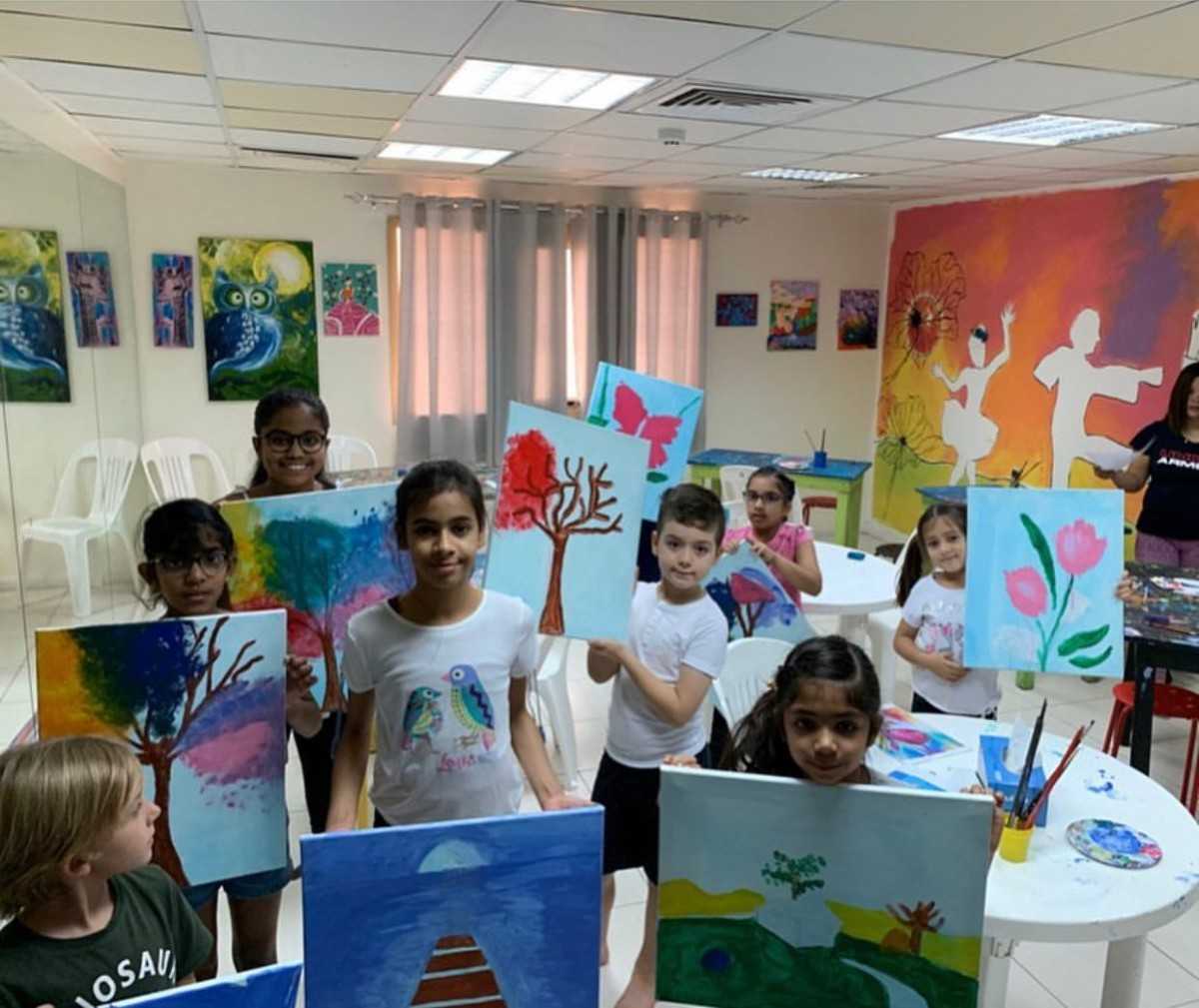 children holding up art paintings in class