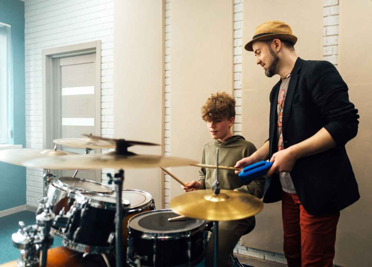 drum lessons being given to child by brother