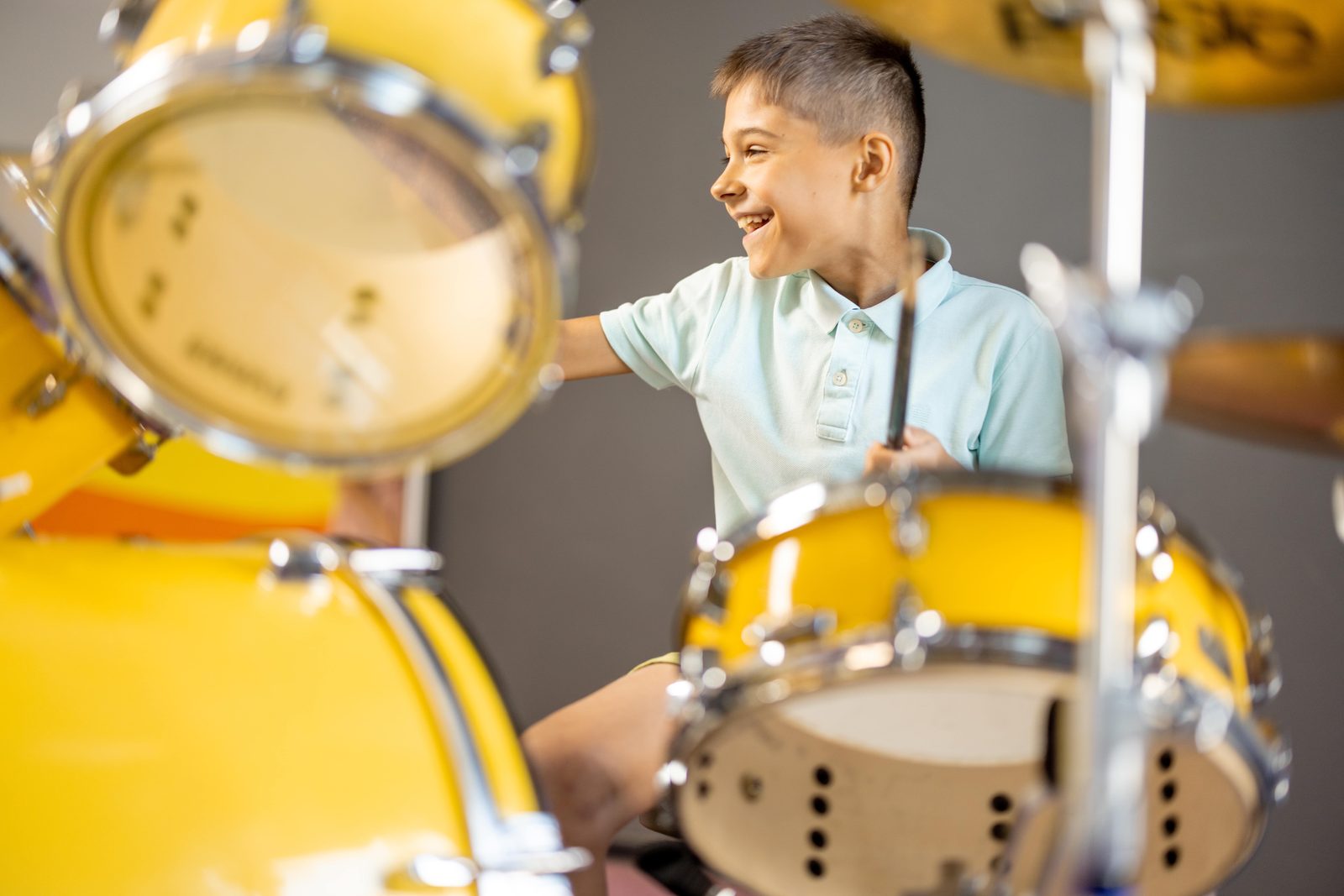 young boy with a big smile while playing yellow drums