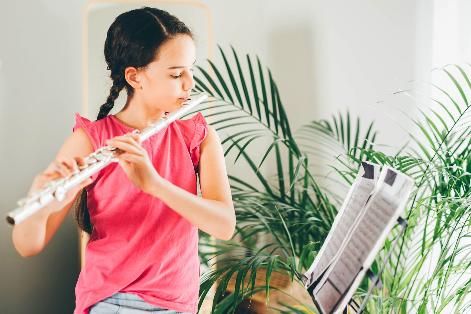 Young girl playing flute while reading music sheet