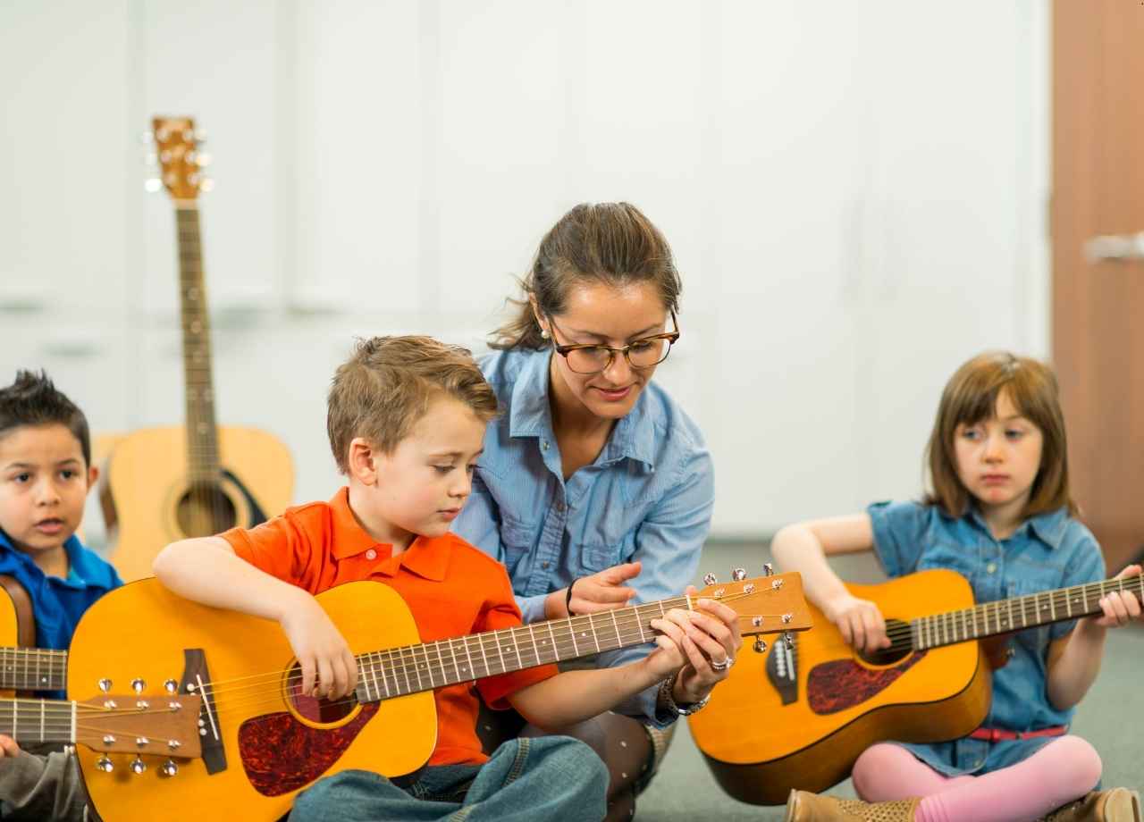 little children teaching each other to play guitar