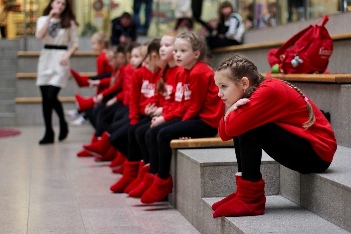 Young little girls in sportive red wear waiting to perform at a dance competition