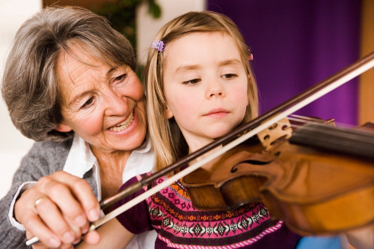 Grandmother teaching young girl to play violin
