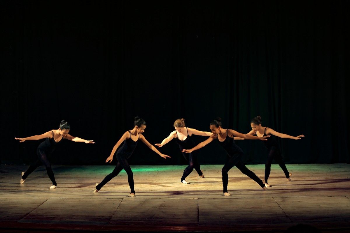 5 girls dancing on stage wearing all black