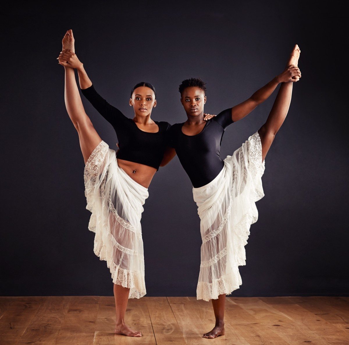 two-young-female-contemporary-dancers-holding legs up in the air