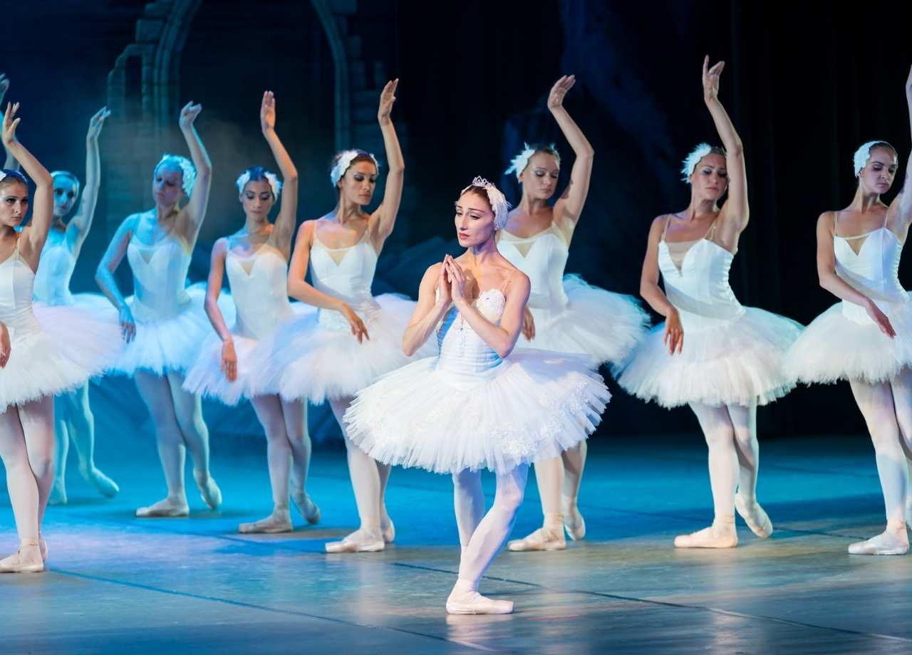 Ballet performance by woman with one at the centreholding her hands together in a ballet pose