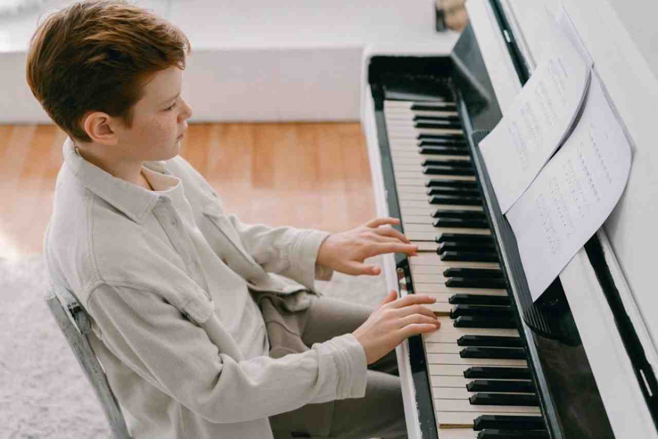 Young boy sitting and playing piaono while reading sheet music