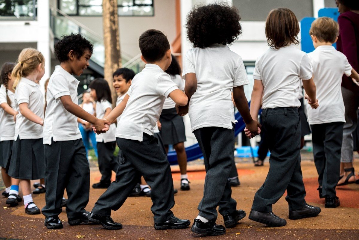 Group of diverse kindergarten students standing holding hands