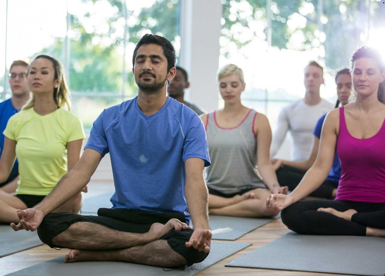 People sitting cross legged in yoga studio on yoga mats