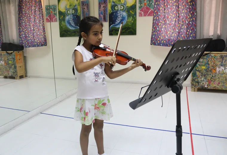 A young violin student playing from a music stand
