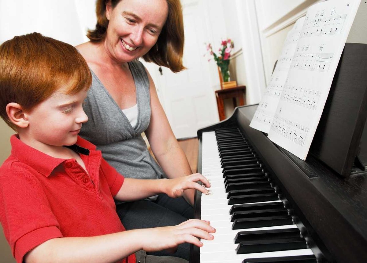 A teacher guiding a young student at the piano