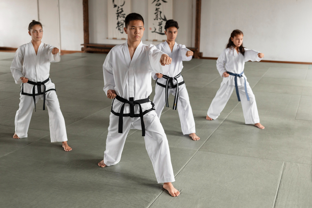 taekwondo class of four young students in white uniforms