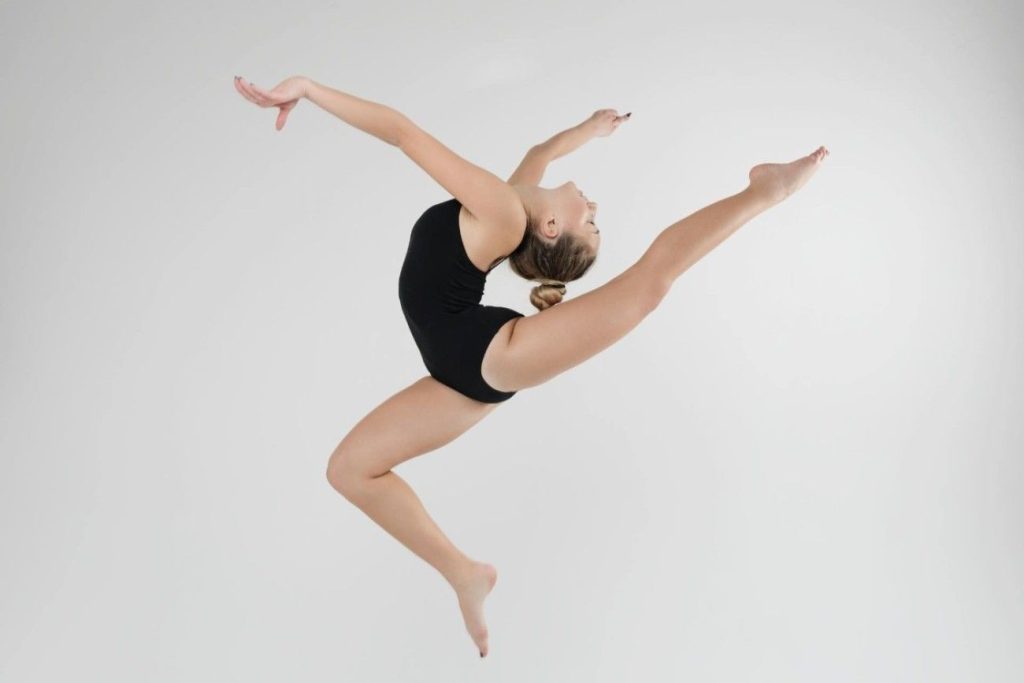 A young ballet dancer in mid air doing a ballet pose